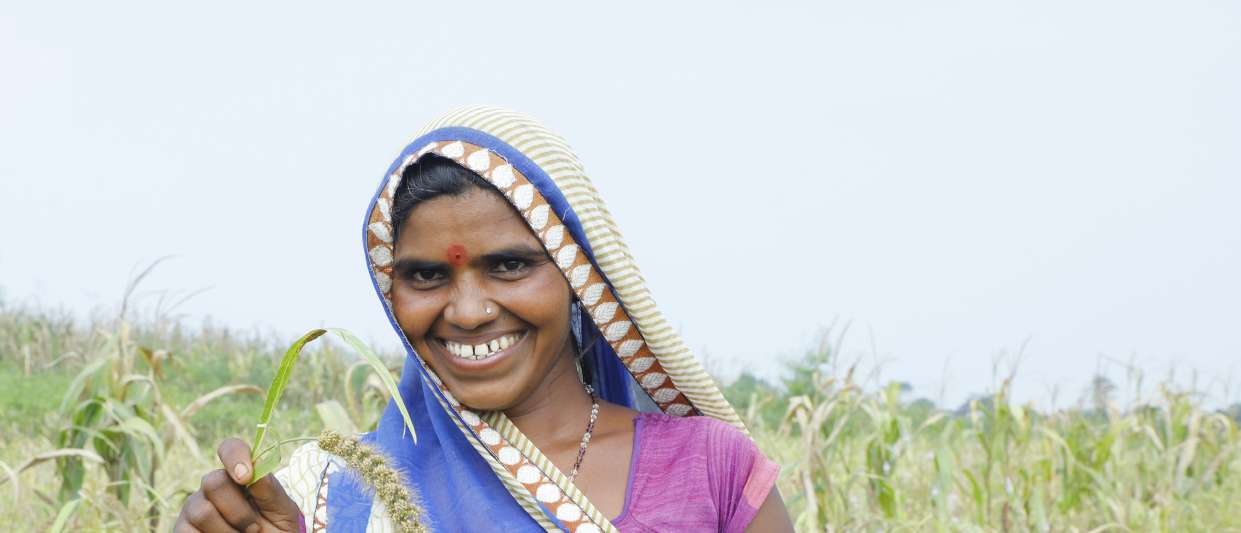 A woman farmer smiling in a field of foxtail millet