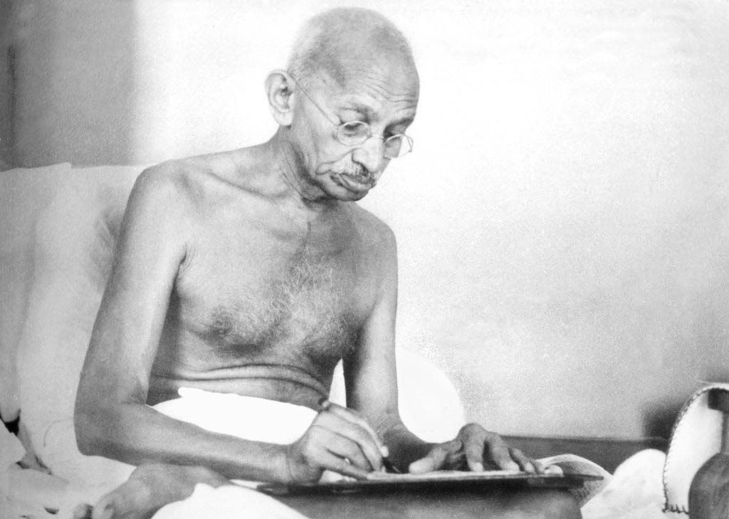 Gandhiji writing on a board resting on his lap, 1942