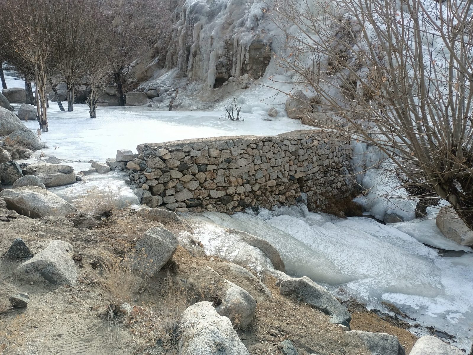 A dry-stone cascade wall of an artificial glacier holding winter ice in Ladakh