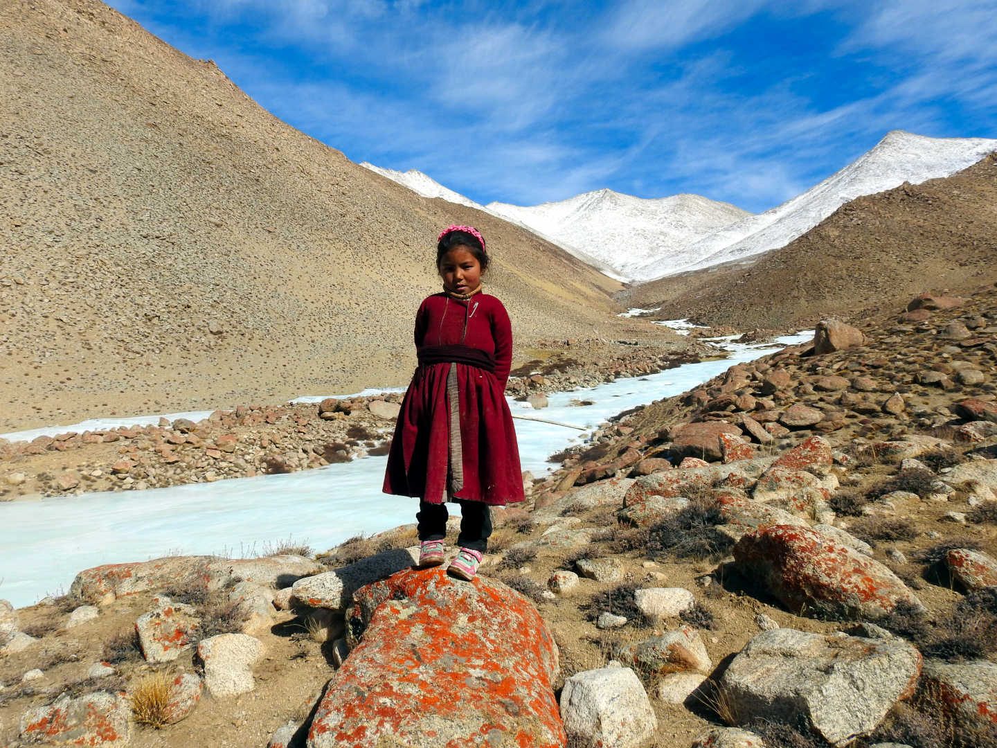 A Ladakhi girl in traditional dress by a frozen stream